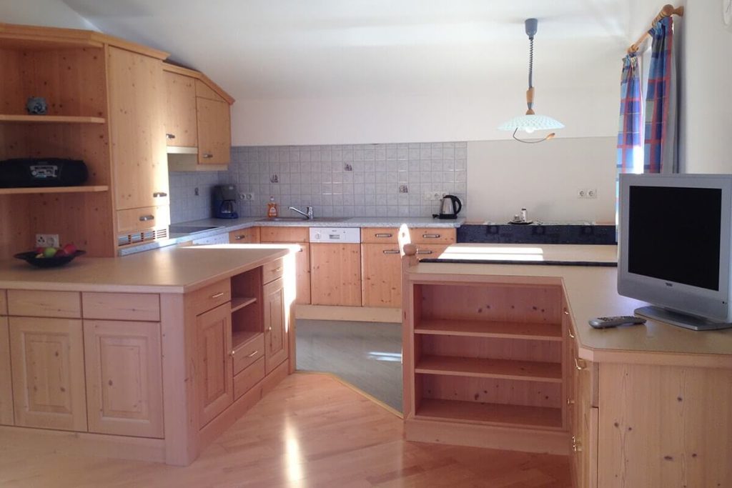 Moderne Küche mit Holzschränken, Kochfeldern und integrierter Sitzecke. Ideal für Familienurlaub.